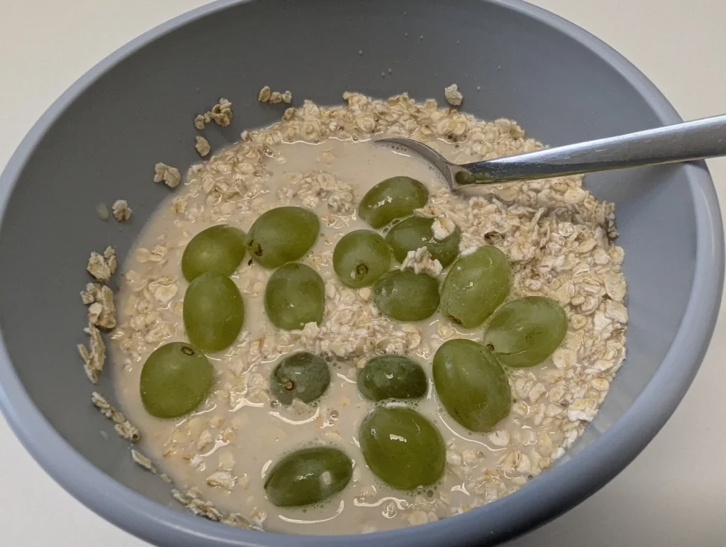 Schale Porridge mit Trauben auf einem Tisch