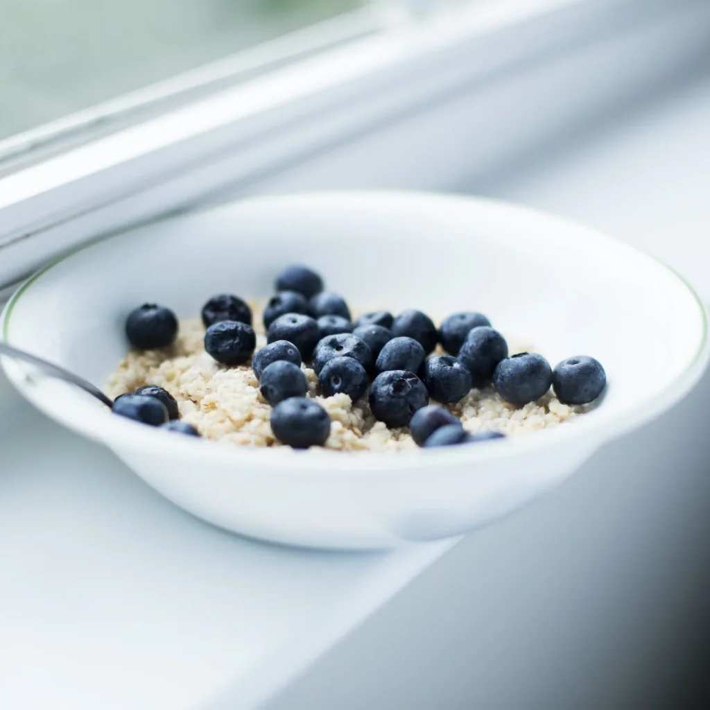 Helle Schale Porridge mit Heidelbeeren am Fenster