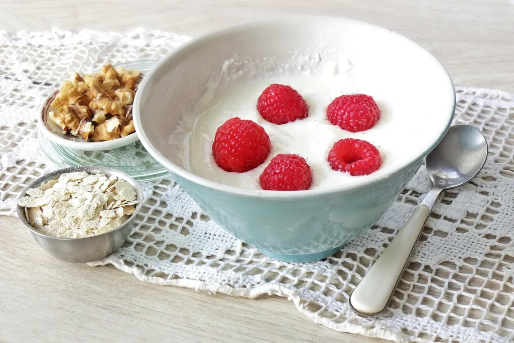Schale Skyr mit Himbeeren, daneben Haferflocken und Walnüsse