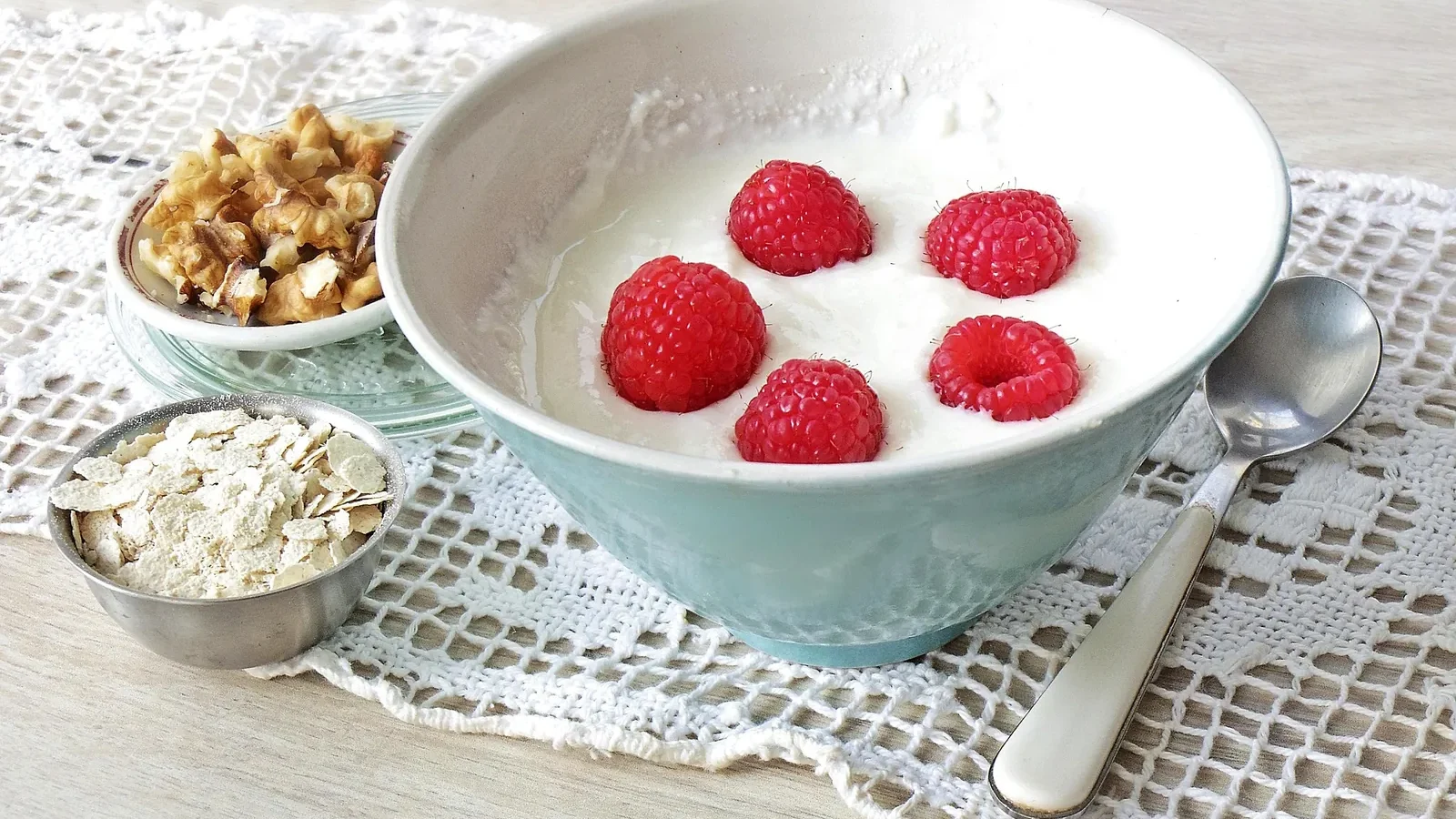 Schale Skyr mit Himbeeren, daneben Haferflocken und Walnüsse